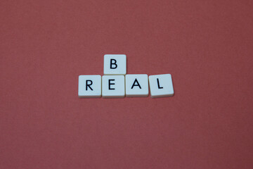 Be real text with plastic letters on red paper sheet. Popular and trendy mobile app called Be Real is spreading around the globe. Be realistic yourself is a good way of living your life.