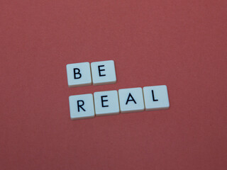 Be real text with plastic letters on red paper sheet. Popular and trendy mobile app called Be Real is spreading around the globe. Be realistic yourself is a good way of living your life.