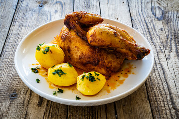 Roast chicken with boiled potatoes on wooden table
