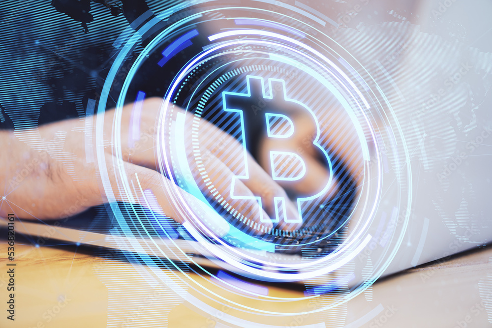 Poster close up of male hands at desktop using laptop with creative glowing bitcoin hologram and map on blu