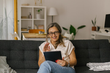 Adult woman having video call at home using tablet