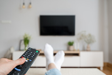 woman watching tv with remote control indoors