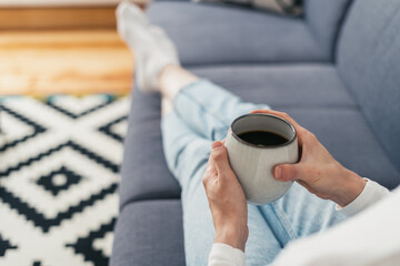 Fototapeta na wymiar woman with cup of coffee sitting on couch indoors