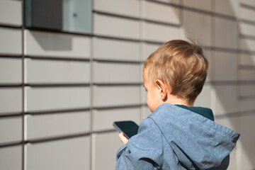 boy holding mobile phone near to Parcel locker Collecting parcel from shopping locker. Child Skans...