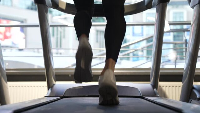 Athlete running on fitness treadmill in gym, back view. Treadmill workout of athlete. Fitness gym