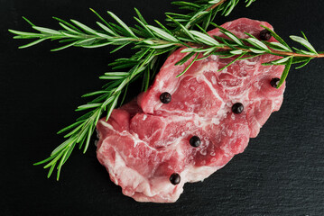 Raw Pork Chops with Pepper and Rosemary  on   dark background