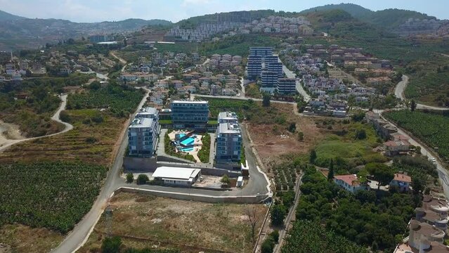 Aerial view of the budget hotel with the outdoors swimming pool. Clip. Southern green city with many trees.