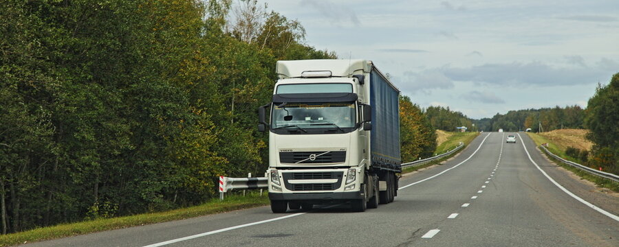 White heavy semi truck VOLVO drive on countryside highway road in autumn. Goods import in Europe