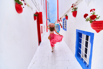 Romantic young traveler girl wearing pink skirt and hat walking alone the aegean street in Bodrum