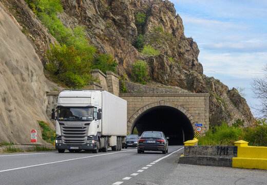 Freight transport by road, by truck. Scania truck on the road, coming out of the road tunnel that crosses the mountain. Romania, Mehedinti. October. 07, 2022