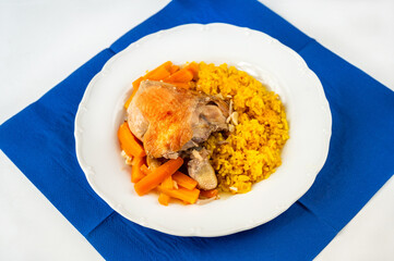 Baked chicken, roasted carrot and stewed turmeric and saffron rice, white plate, blue towel.