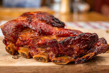 Juicy baked pork rib with crispy crust on wooden kitchen board on rustic table-cloth.