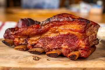 Baked pork rib with crispy crust on wooden kitchen board on wooden kitchen board, closeup.