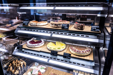 Confectionery showcase of broad variety of sweets and desserts behind the refidgerated glass