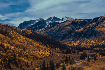 Crested Butte Colorado with autumn and winter conditions mixing the snow-capped mountains and golden yellow aspens in a river meadow valley 