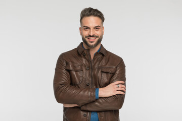 happy bearded man with brown jacket crossing arms and smiling