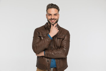 Fototapeta premium smiling young man holding hand to chin and being happy