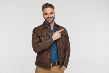 Fototapeta premium handsome man in brown leather jacket pointing finger to side and smiling