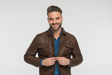 excited casual man with denim shirt buttoning brown leather jacket