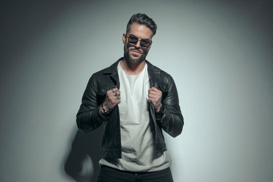 casual man pulling his leather jacket, wearing sunglasses