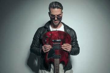 sexy rocker holding his electric guitar upside down