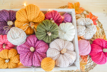 Obraz na płótnie Canvas colorful woolen crochet pumpkins with woolen balls, autumn leaves and lights on a wooden tray