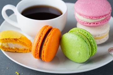 French colored macaroons with white cup of coffee