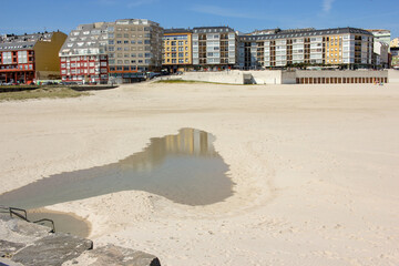 buidings reflected in some sea water in the beach