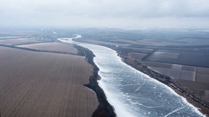 Frozen river covered with snow. Frozen river in the snow. Winter landscape, top view