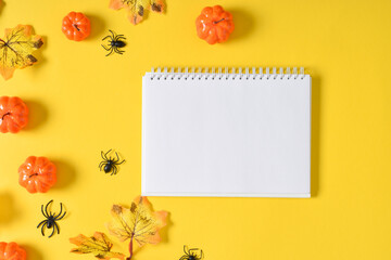 A mock-up of a Halloween notebook with pumpkins and spiders on a yellow background with a place for text.