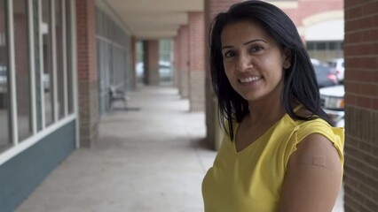 pretty indian woman smiles at camera with band aid on arm