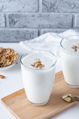 Kefir, buttermilk or yogurt with granola. Yogurt in glass on light background. Probiotic cold fermented dairy drink. Gut health, fermented products, healthy gut flora concept. Copy space