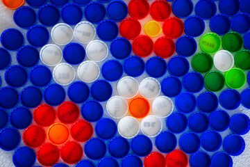 Flowers mosaic decoration made of colorful plastic bottle caps . Summer season concept. Handmade crafts. Recycling art.