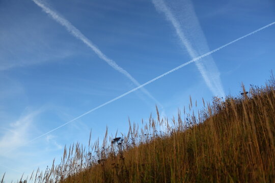 Traces from the planes in the blue sky over the field hill meadow in autumn