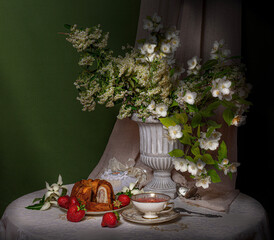 a bouquet of flowers in a vase with a dessert with strawberries on a green background