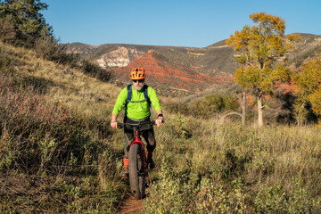 Obraz premium a senior male riding a fat mountain bike on a single track trail in Red Mountain Open Space in Colorado, fall scenery