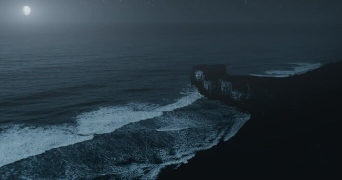 Rocky cliffs and waves at moonlight night aerial view. Landmark Etretat, Normandy, France travel. Moon glow above ocean water. Atmospheric rock silhouette. Cinematic midnight starry wavy seascape.