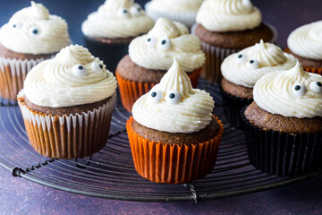 Close up of pumpkin spice cupcakes topped with ghost shape icing and eyeballs.