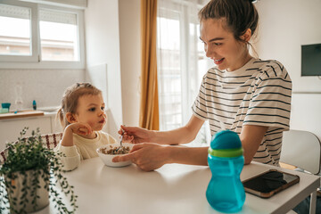 Loving mom feeding cereal to her calm child