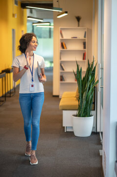 Cute office worker waving to her colleagues while passing by their room