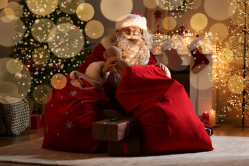 Santa Claus with gifts in bags in room at Christmas night