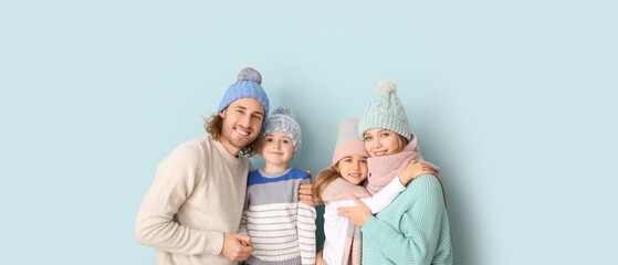 Fototapeta na wymiar Happy family in winter clothes on light blue background