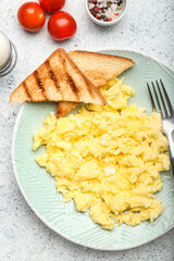 Plate with tasty scrambled eggs on white background, closeup