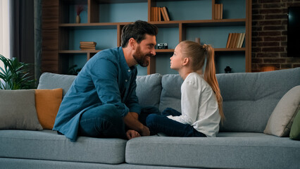 Playful caucasian young family daddy and small daughter sitting comfortable on couch loving cute...