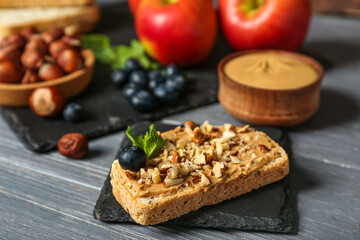 Tasty sandwich with nut butter and walnuts on dark wooden table, closeup