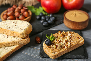 Tasty sandwich with nut butter and walnuts on dark wooden table, closeup
