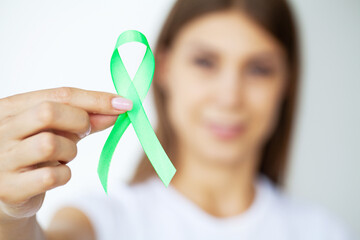 Green ribbon in hand as symbol to awareness Lymphoma cancer