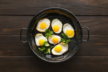 Frying pan with tasty fried quail eggs on dark wooden background