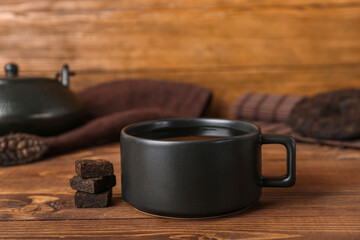 Black cup of puer tea on wooden background, closeup