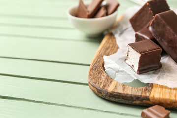 Board with tasty bird's milk candies on color wooden background, closeup